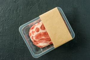 Raw marbled pork steak in vacuum packaging on black background, top view, logo mockup for design photo