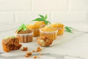 Marijuana cupcake muffins and cannabis leaves on a white marble table. Home cooked photo