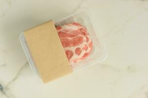 Raw pork steakes vacuum Packed on marble background, top view, mockup for designers. photo