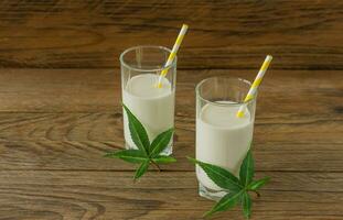 Glasses with Cannabis herbal vegan gluten and lactose free milk and cannabis leaves on wooden table