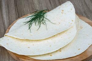 Tortillas on wooden board and wooden background photo