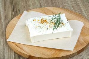 Feta cheese on wooden board and wooden background photo