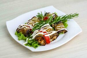 Aubergine roll on the plate and wooden background photo