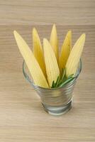 Baby corn in a bowl on wooden background photo