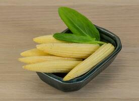 Baby corn in a bowl on wooden background photo