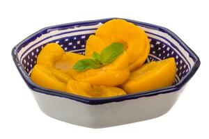 Marinated peaches in a bowl on white background photo