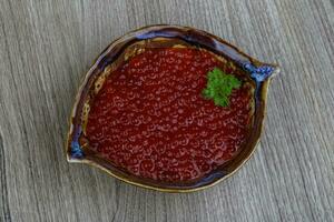 caviar rojo en un recipiente sobre fondo de madera foto