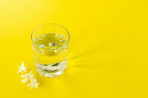 a glass of pure water on yellow background. copy space for text. consept of health life and diet photo