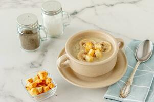 Mushroom cream soup with herbs and spices in brown bowl on marble table. photo