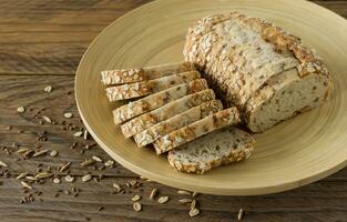 Gluten-free vegan bread with no animal products. Vegetarian bread with oatmeal, banana flavor on a plate on a wooden rustic table, sliced and ready to serve. photo