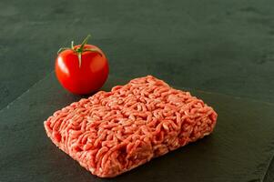 Raw minced beef meat on a slate with tomato. photo