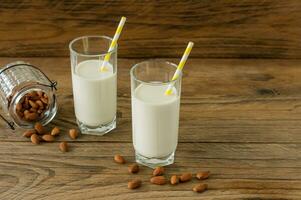 Almond milk in glass with almonds on wooden table photo