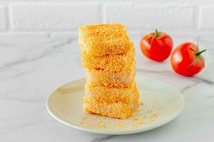 breaded fish patties on a plate prepared to cook photo