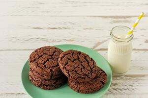 Chocolate cookies for breakfast with a glass of milk on a white wooden table. photo