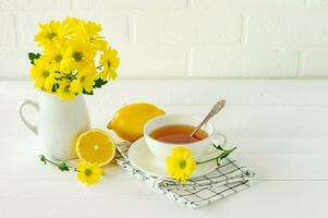 Morning tea with lemon and yellow chrisantemum flowers photo