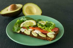 Sandwich with smoked salmon soft cheese, lattice and avocado. Concept for a tasty and healthy meal. Food on a plate. photo