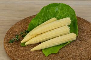 Baby corn on wooden board and wooden background photo