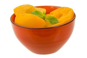 Marinated peaches in a bowl on white background photo