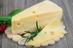 Yellow cheese on wooden board and wooden background photo