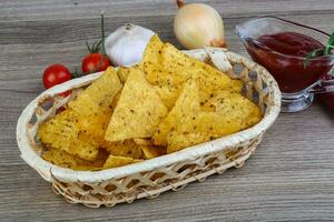 Nachos in a basket on wooden background photo