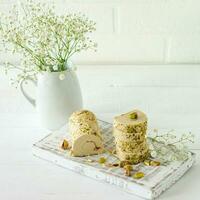 Halva with pistachio served on white wooden desk with flowers photo