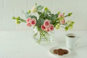 ramo de rosas, eustoma y eucalipto en un elegante jarrón de cristal sobre una mesa. composición de flores para la decoración de interiores. foto
