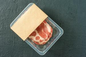 Raw marbled pork steak in vacuum packaging on black background, top view, logo mockup for design photo