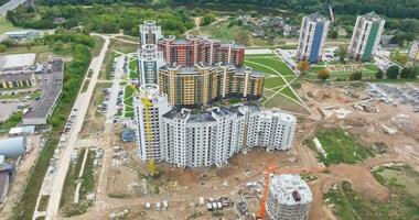 aerial panoramic view and circular flight near tower crane and modern unfinished multi-storey high buildings under construction site video