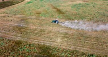 aerial view on tractor cultivator or seeder plows the land, prepares for crops. dust on field video