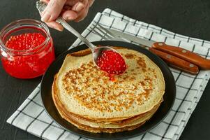 crepes rusos tradicionales blini apilados en un plato con caviar rojo sobre fondo de madera. Maslenitsa comida tradicional del festival ruso. comida rusa, cocina rusa. de cerca. foto