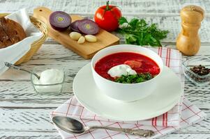 borscht ruso tradicional ucraniano con ajo y pan. un tazón de borscht de remolacha roja sobre una mesa de madera blanca. sopa de remolacha. cocina tradicional eslava. foto