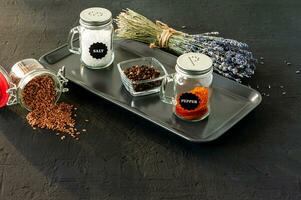 pepper and salt glass shakers on a black concrete backgroun with copy space photo