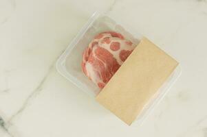 bistecs de cerdo crudo envasados al vacío sobre fondo de mármol, vista superior, maqueta para diseñadores foto