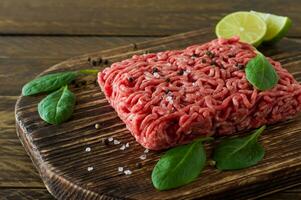 Raw minced beef meat on a wooden cutting board with vegetables and spices. Cooking and healthy eating concept. photo