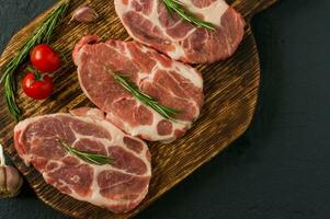 Pork neck raw meat for fresh Chop steaks on wooden cutting board. Top view. photo