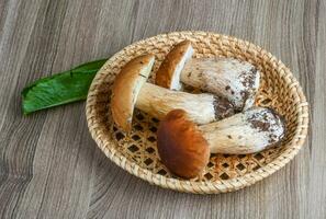 Wild Mushrooms in a basket on wooden background photo