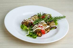 Aubergine roll on the plate and wooden background photo