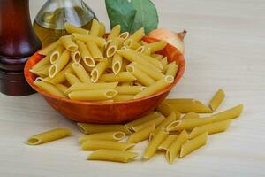 Raw penne on wooden background photo