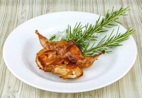 Grilled quail on the plate and wooden background photo