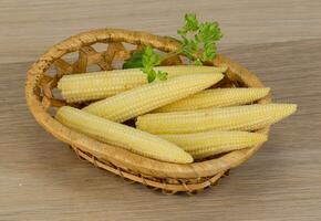 Baby corn in a basket on wooden background photo