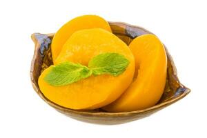 Marinated peaches in a bowl on white background photo