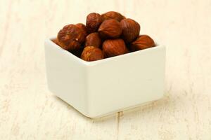 Hazelnut heap in a bowl on wooden background photo