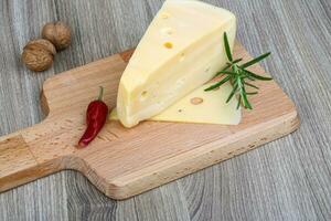 Yellow cheese on wooden board and wooden background photo