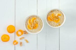 Light calorie porridge. Oatmeal with juicy tangerines and flax-free flax seeds in a bowls on sackcloth, white background. Low-calorie porridge recipe. photo