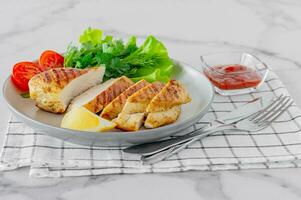 Grilled chicken breasts served on a plate with salad and vegetables. Dietary food photo