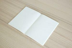 maqueta de libro de papel abierto en blanco sobre fondo de mesa de madera foto