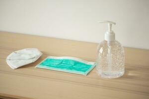 Medical face mask with alcohol sanitizer gel hand wash on wood table for covid-19 Coronavirus prevention concept photo