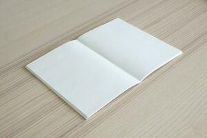maqueta de libro de papel abierto en blanco sobre fondo de mesa de madera foto