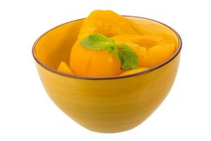 Marinated peaches in a bowl on white background photo