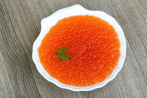 Red caviar in a bowl on wooden background photo